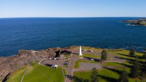 Kiama, a resort town in Australia. An aerial view of the picturesque rocky headland. A white lighthouse stands on the ocean.